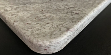 Close-up of a speckled granite countertop edge with rounded corners.
