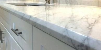Close-up of a marble countertop with a sink and white cabinets.