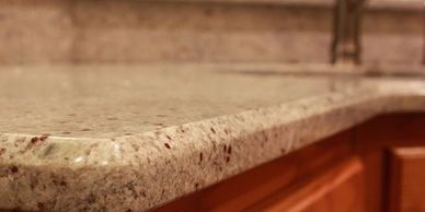 Close-up of a polished granite kitchen countertop with wooden cabinets.