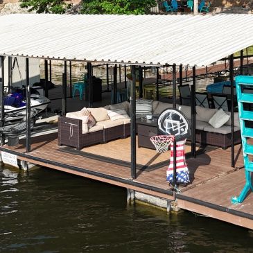 Covered lakeside dock with outdoor seating and a basketball hoop.