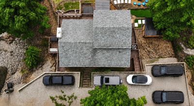 Aerial view of a house with parked cars around.