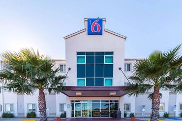 Exterior of a Motel 6 building with palm trees.