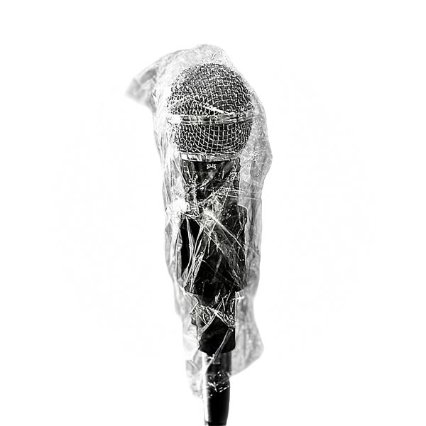 A microphone wrapped in plastic and sitting on top of a stand.