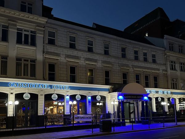 Night view of Carmichael Hotel with blue and white lights illuminating the facade.