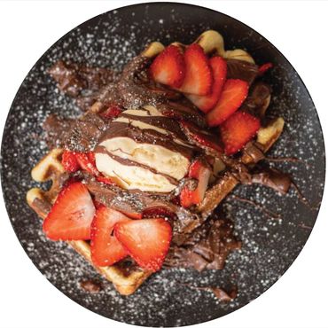 Freshly baked waffles topped with strawberries and whipped cream