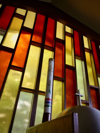 Colorful stained glass window with a candle and cross.