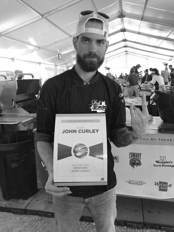 Man holding award certificate for John Curley at a burger competition.