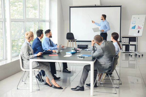 Team at a table with teacher at white board image.
