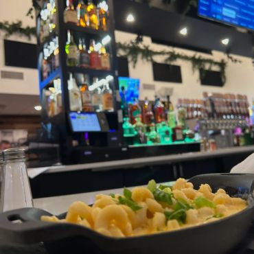 Close-up of creamy macaroni and cheese with a bar in the background.
