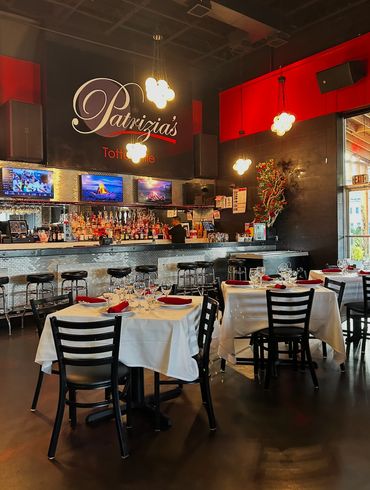 Elegant restaurant interior with white tablecloths and a well-stocked bar.