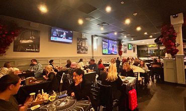 Cozy restaurant with many diners and multiple TVs on the walls.