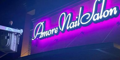 Bright neon sign for Amore Nail Salon at night.