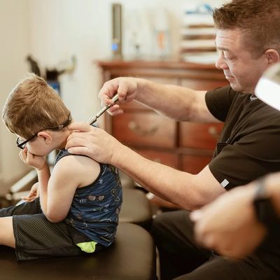 chiropractor using activator for chiropractic adjustment to pediatric patient