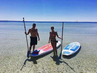 2 paddleboarders in shallow water with blue sky in background. www.whatsuppaddlesports.com