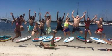 12 white and black kayakers jumping same timecelebrating on the beach. www.whatsuppaddlesports.com