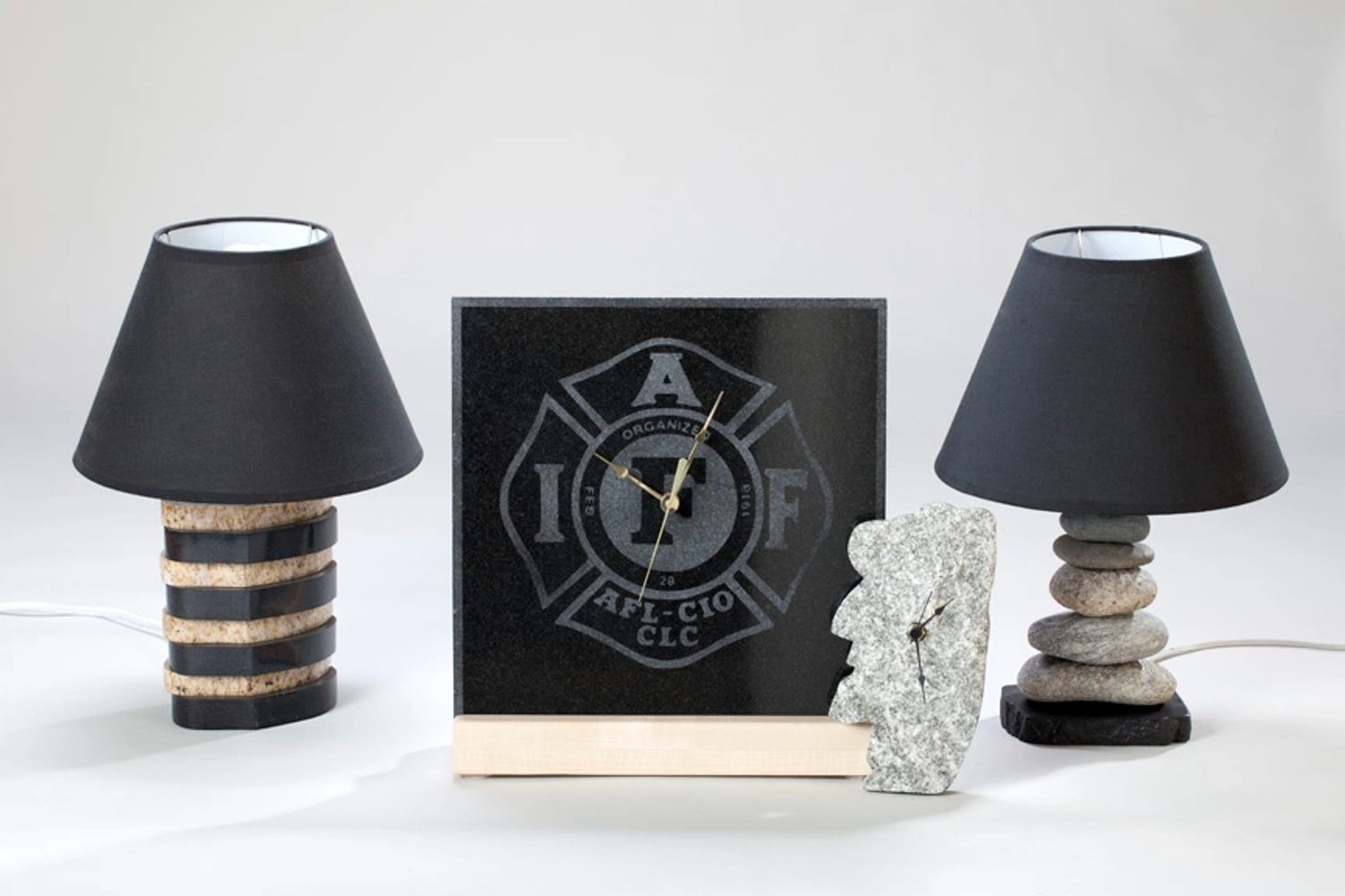 Two stone-based lamps and two unique clocks on a white surface.