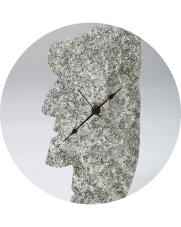 Gray granite clock shaped like a Moai statue profile with black clock hands.