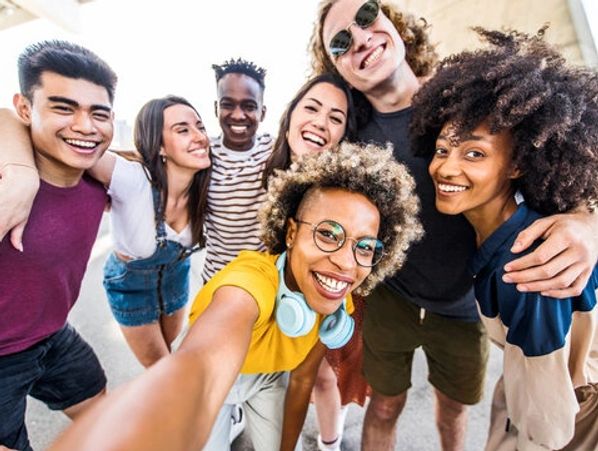 A diverse group of friends happily taking a selfie together outdoors.