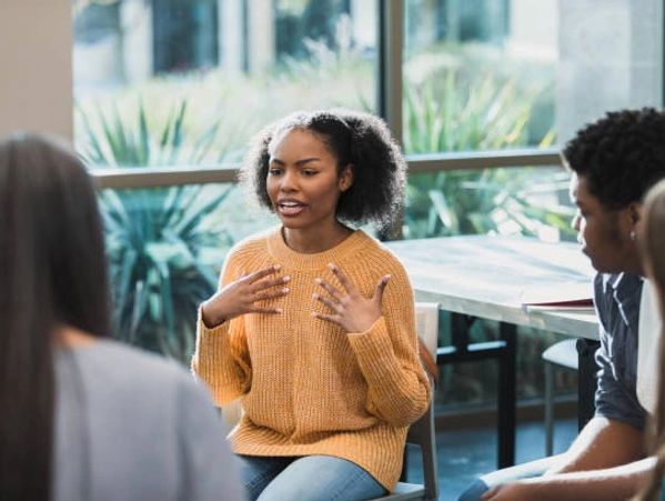 Young woman speaking passionately in a group discussion.