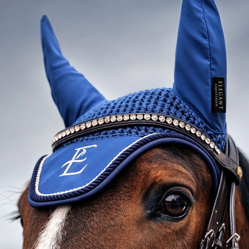 Close-up of a horse wearing an elegant blue ear bonnet with rhinestones.