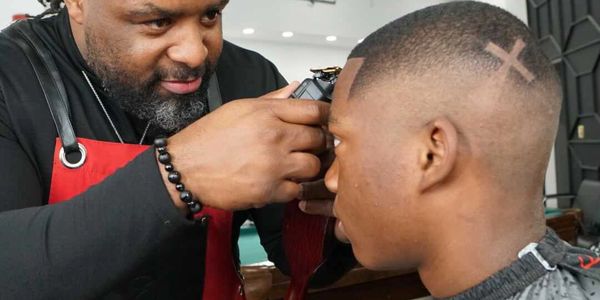 Barber Sirento Hardwell performing a precise hairline lineup at Unique Kutz Grooming Lounge in Sugar