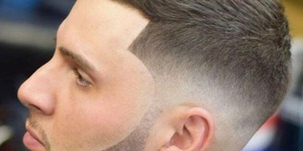 Close-up of a man with a sharp, clean fade haircut and well-groomed beard.
