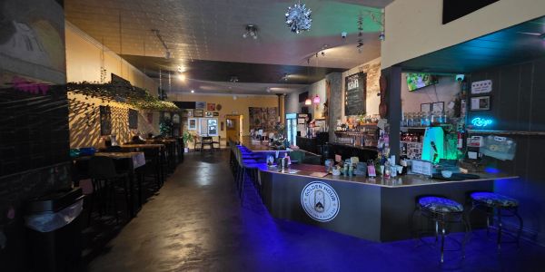 Cozy bar with purple lighting and hanging plants.