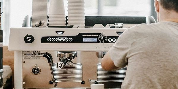 Barista preparing coffee using a professional espresso machine.