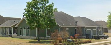 A suburban house with a basketball hoop and convertible car in the driveway.