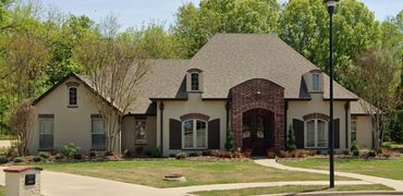 Arched dormers and entry with mixture of brick and stucco exterior.