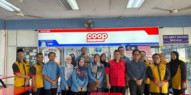 Group photo of people standing inside a Coop store with Malaysian flags.