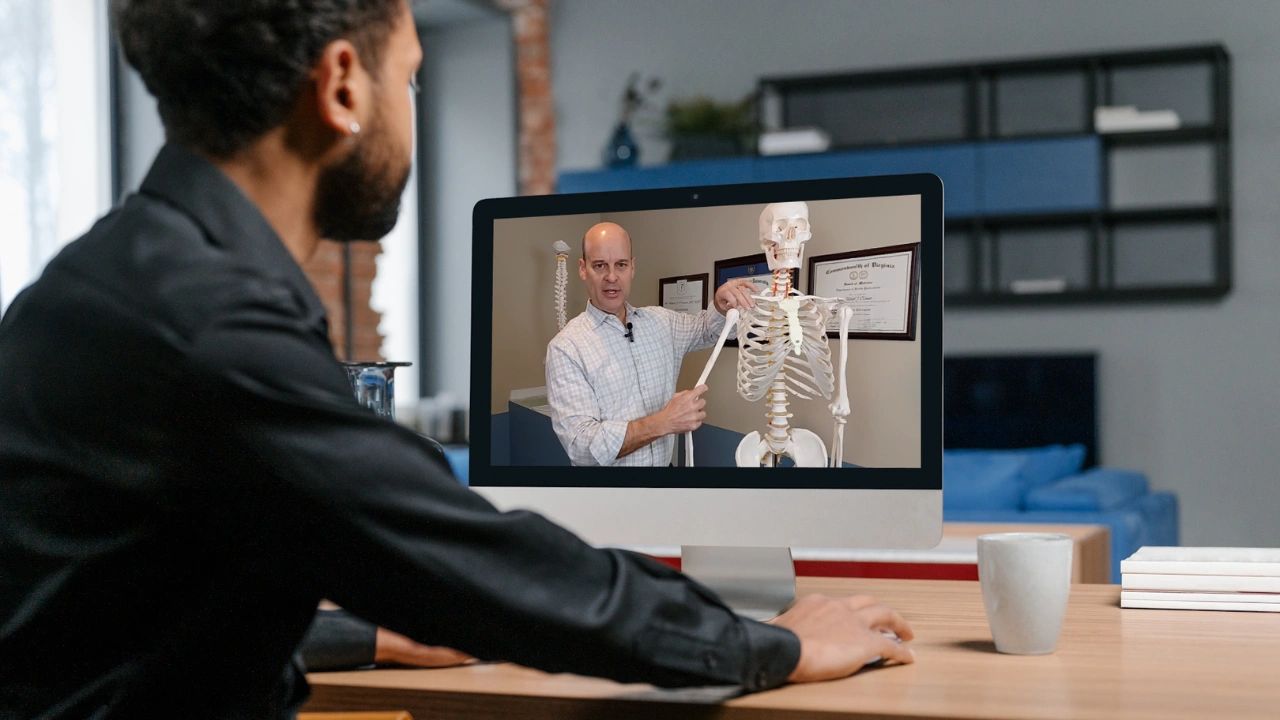 Man getting a PT second opinion during an online consultation, with a therapist and skeleton model