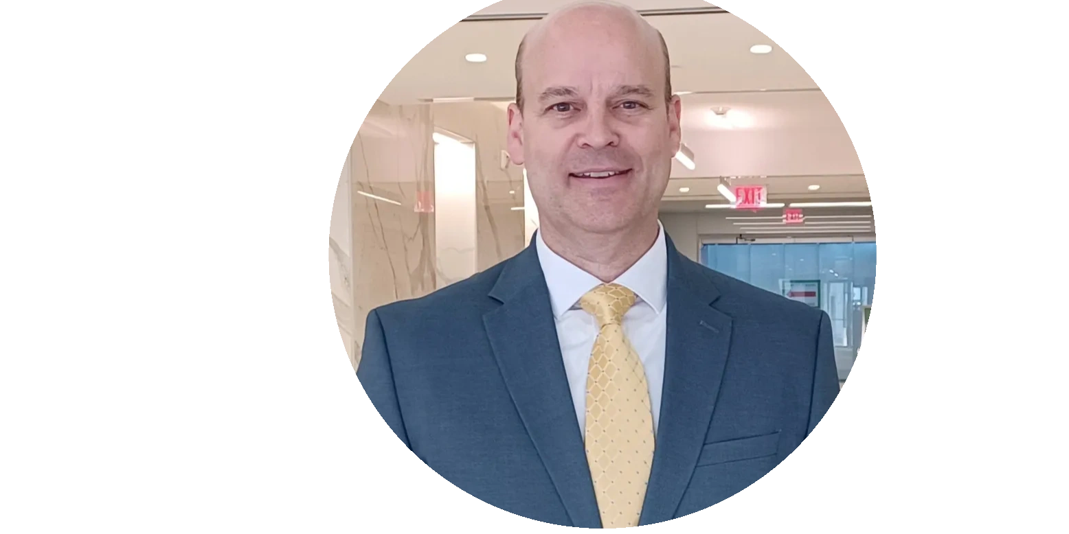 Smiling man in a suit and yellow tie in an office setting.