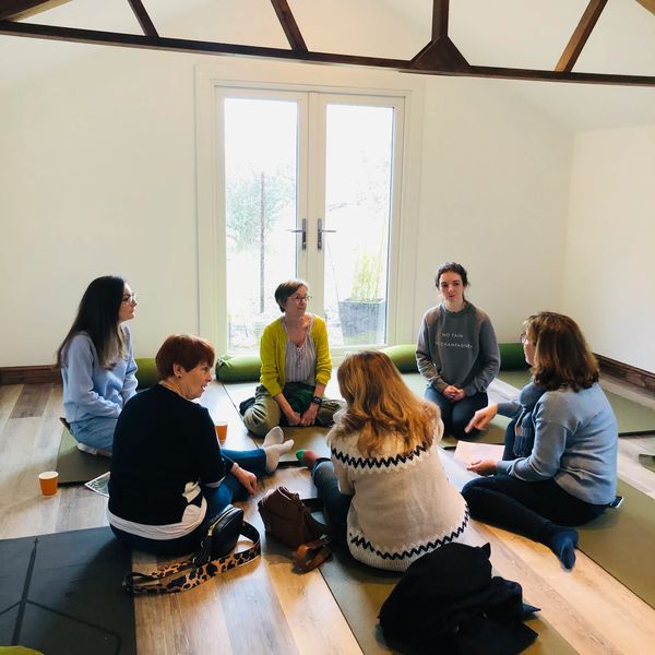 A group of women sitting on the ground in a circle at a Lusso Yoga workshop