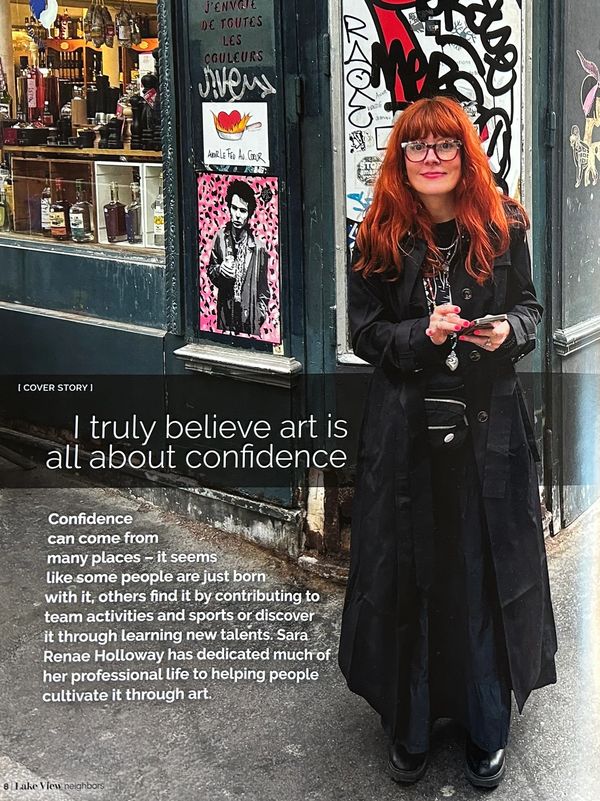 A confident woman in black standing by a street corner with artistic posters.
