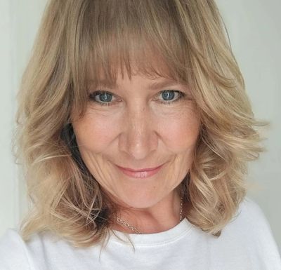 Smiling woman with blonde hair and blue eyes in a white top.