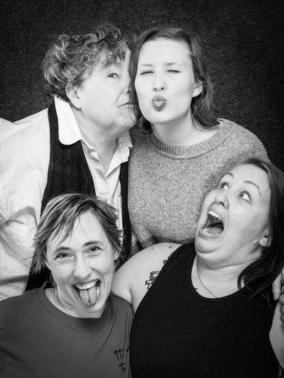 Four women making funny faces in a playful black-and-white portrait.