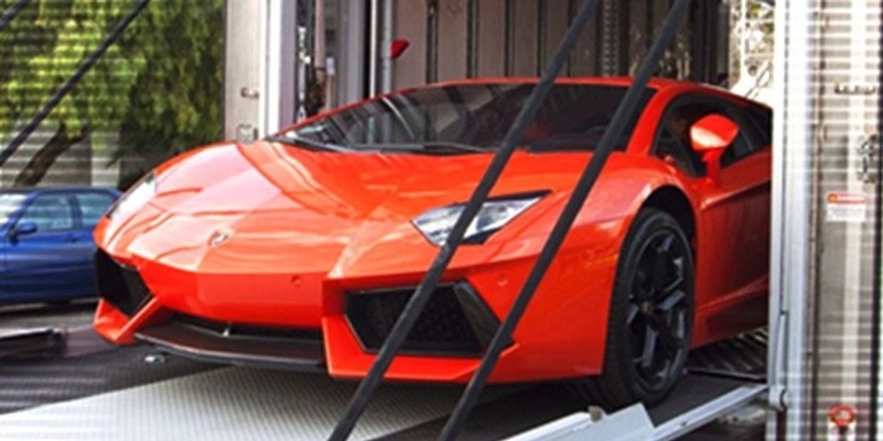 Bright orange sports car inside a transport container.