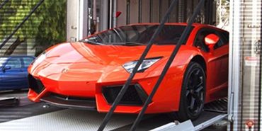 A bright orange sports car inside a transport container.