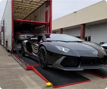 Luxury black sports car being unloaded from a trailer.