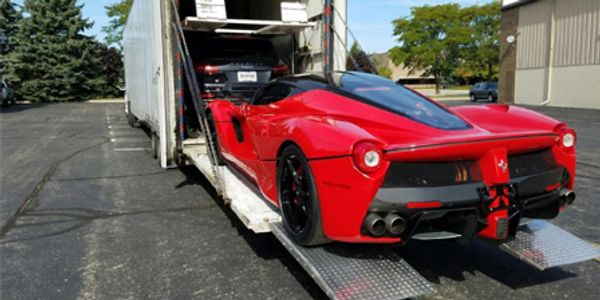 Red sports car being loaded into a trailer.