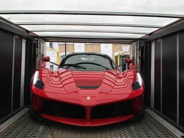 A red Ferrari sports car inside a transport container.