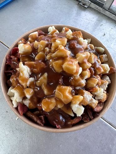 A bowl of poutine topped with cheese curds and gravy.