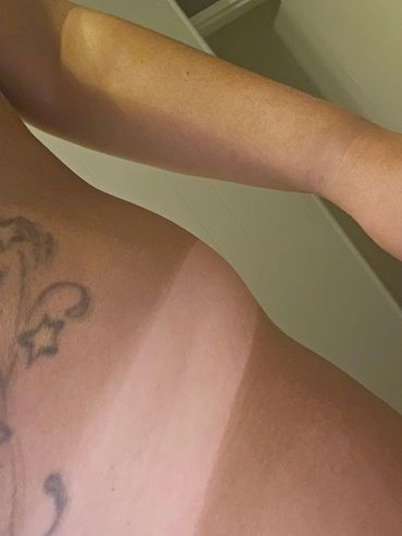 Visible tan lines on an arm and shoulder with a tattoo.