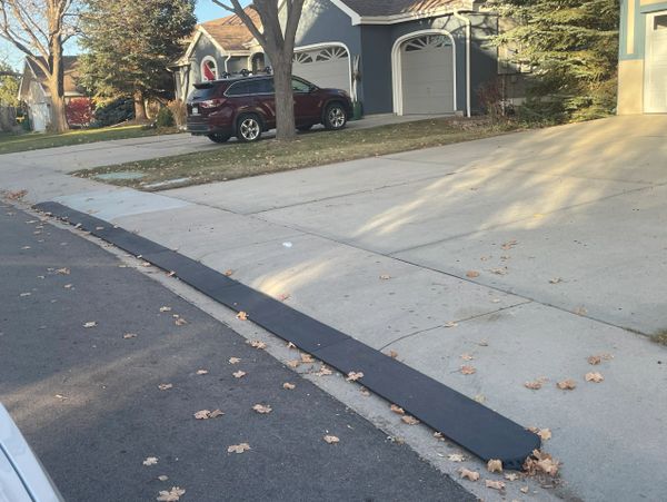 A black curb ramp installed on a sidewalk edge next to a street.