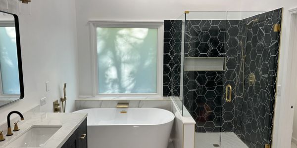 Finished bathroom remodel featuring a freestanding tub, custom black tile shower, modern vanity, and