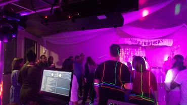 People celebrating a birthday party with neon lights and decorations.