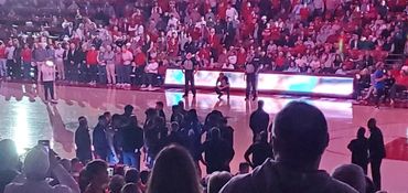 Crowded indoor basketball arena with fans and players on court.