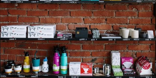 display shelves with coffee and cups sitting on them in front of brick wall