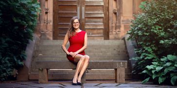 Woman in a red dress sitting on a bench outdoors.